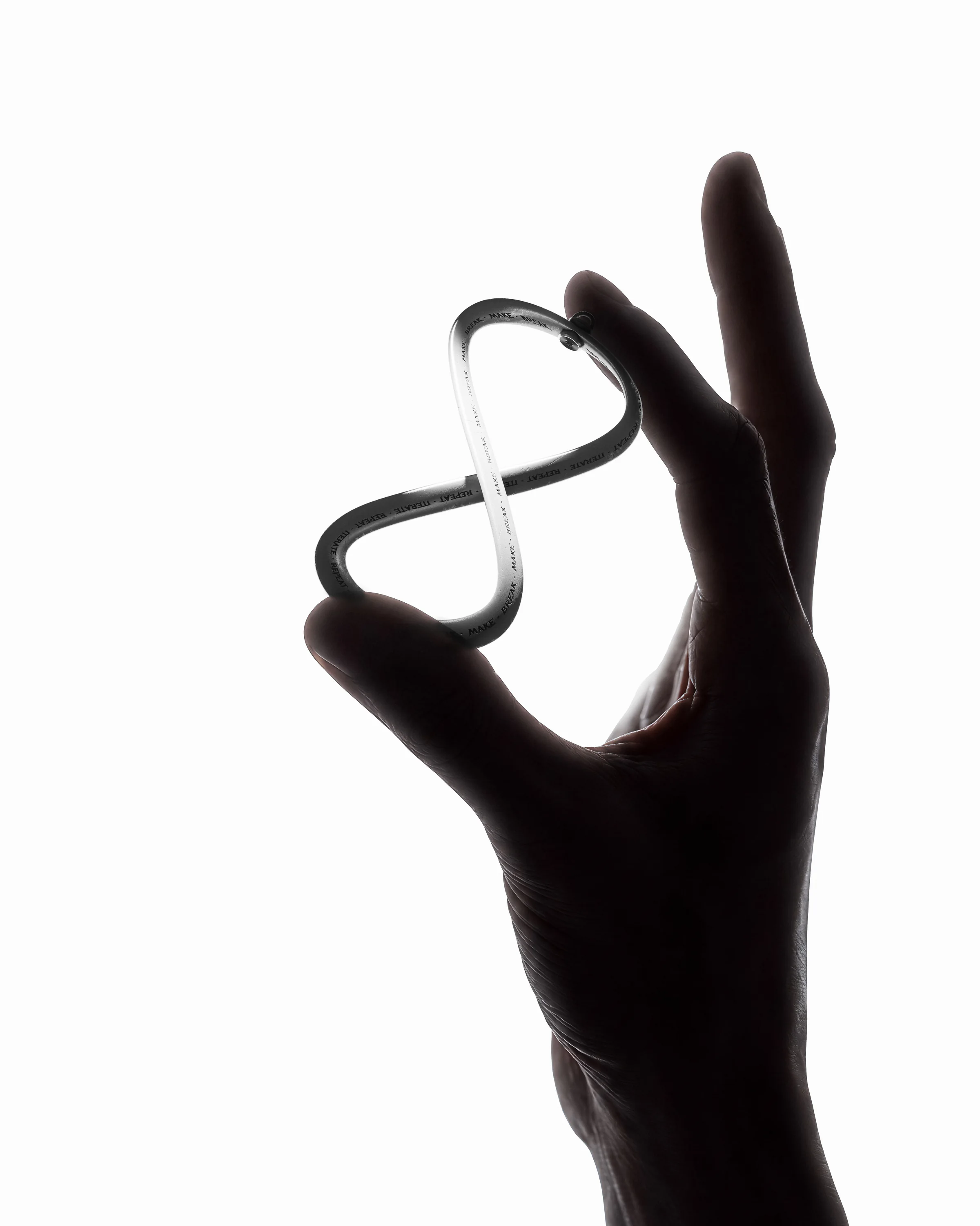 Möbius keychain loop held between a person's fingers to show scale