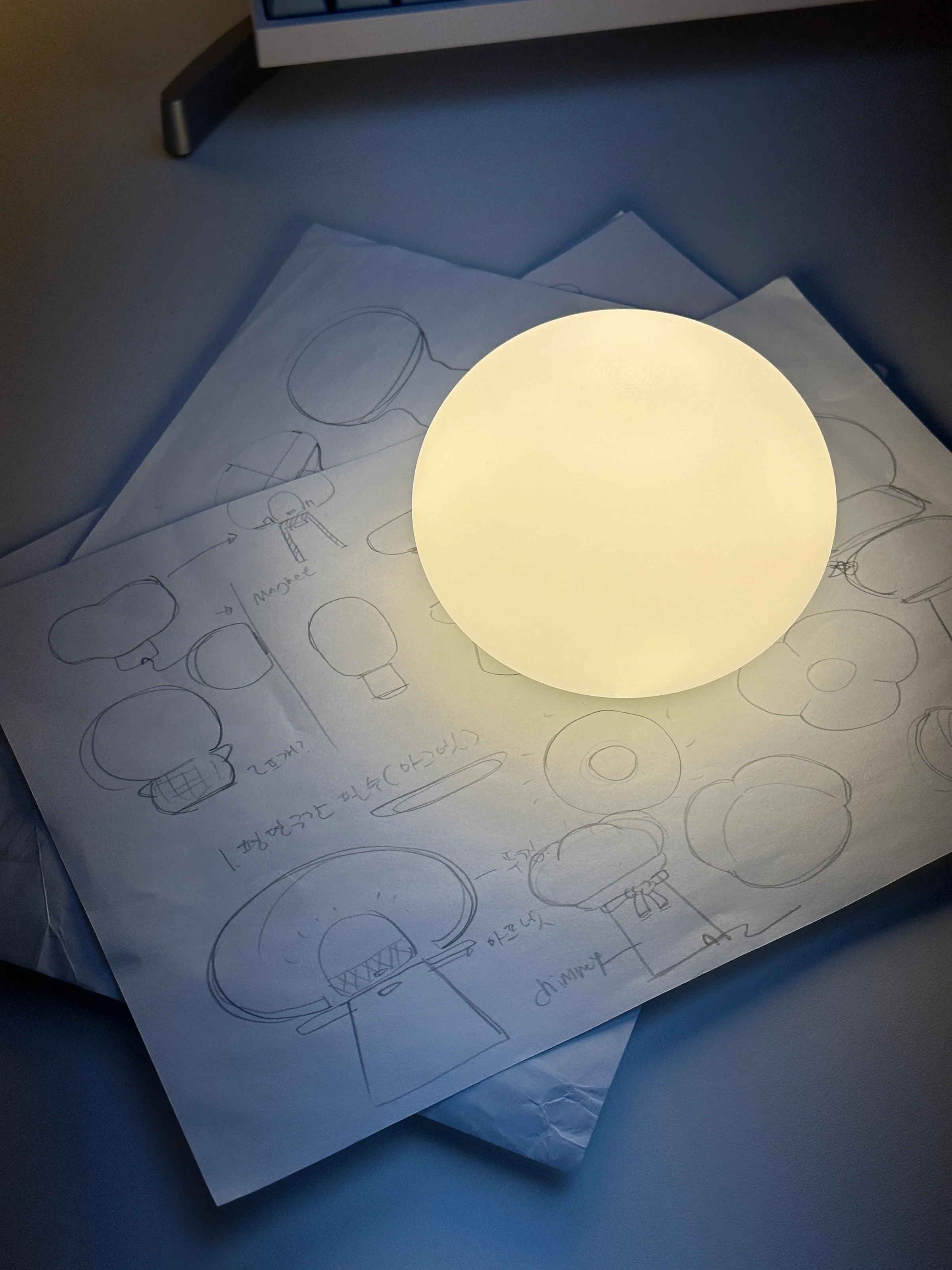 Illuminated Project Present 2025 lamp prototype placed on concept sketches
